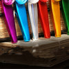 A row of colorful silver aluminum kazoo tubes resting on a stack of old books.