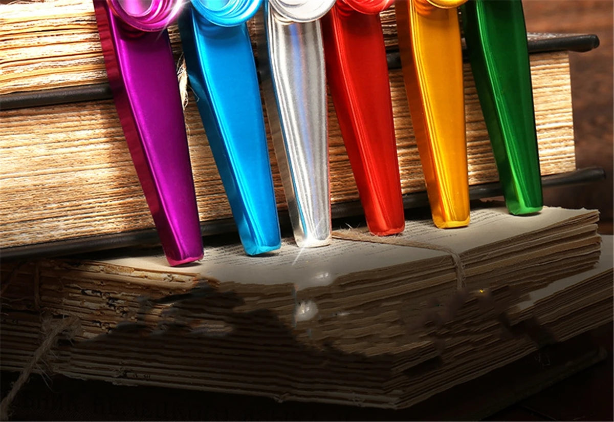A row of colorful silver aluminum kazoo tubes resting on a stack of old books.
