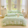 A light green printed duvet cover set with matching pillowcases displayed on a bed near a large window.