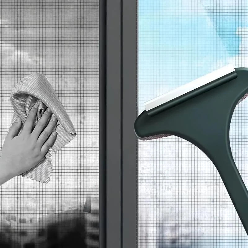 A hand is using a green window cleaning brush to wipe a glass window pane.
