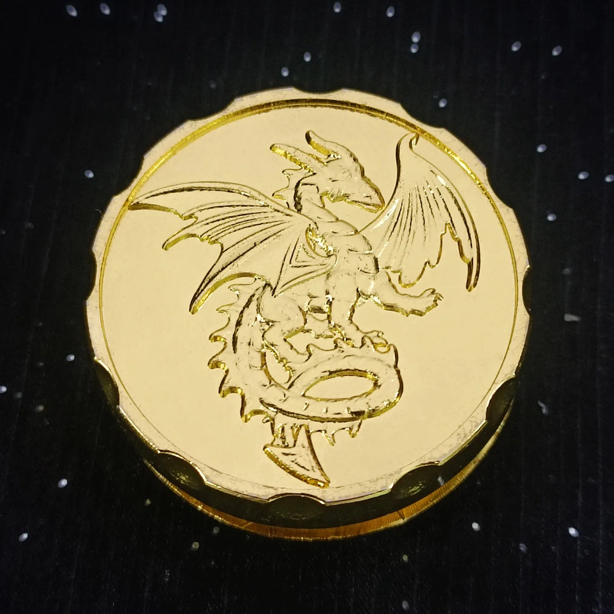 A gold metal fingertip gyro roulette dice for tabletop games with a winged creature design.