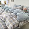 A plaid bedding set featuring gray and beige tones with a subtle check pattern on a bed.
