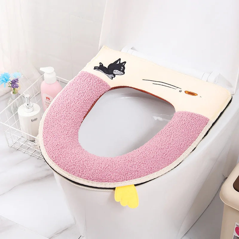 Tapa impermeable rosa suave con diseño de gato negro en un inodoro blanco.