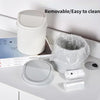 A white compact covered desktop trash bin with a flip lid and related cleaning accessories shown on a white surface.