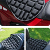 Black ergonomic motorcycle seat cushion with a textured pattern shown on a red motorcycle seat.
