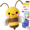 A yellow and brown crocheted bee toy with wings, accompanied by yarn and tools for crafting.