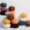 A stack of soft, round plush pillows shaped like Halloween pumpkins in various colors including blue, pink, orange, and green