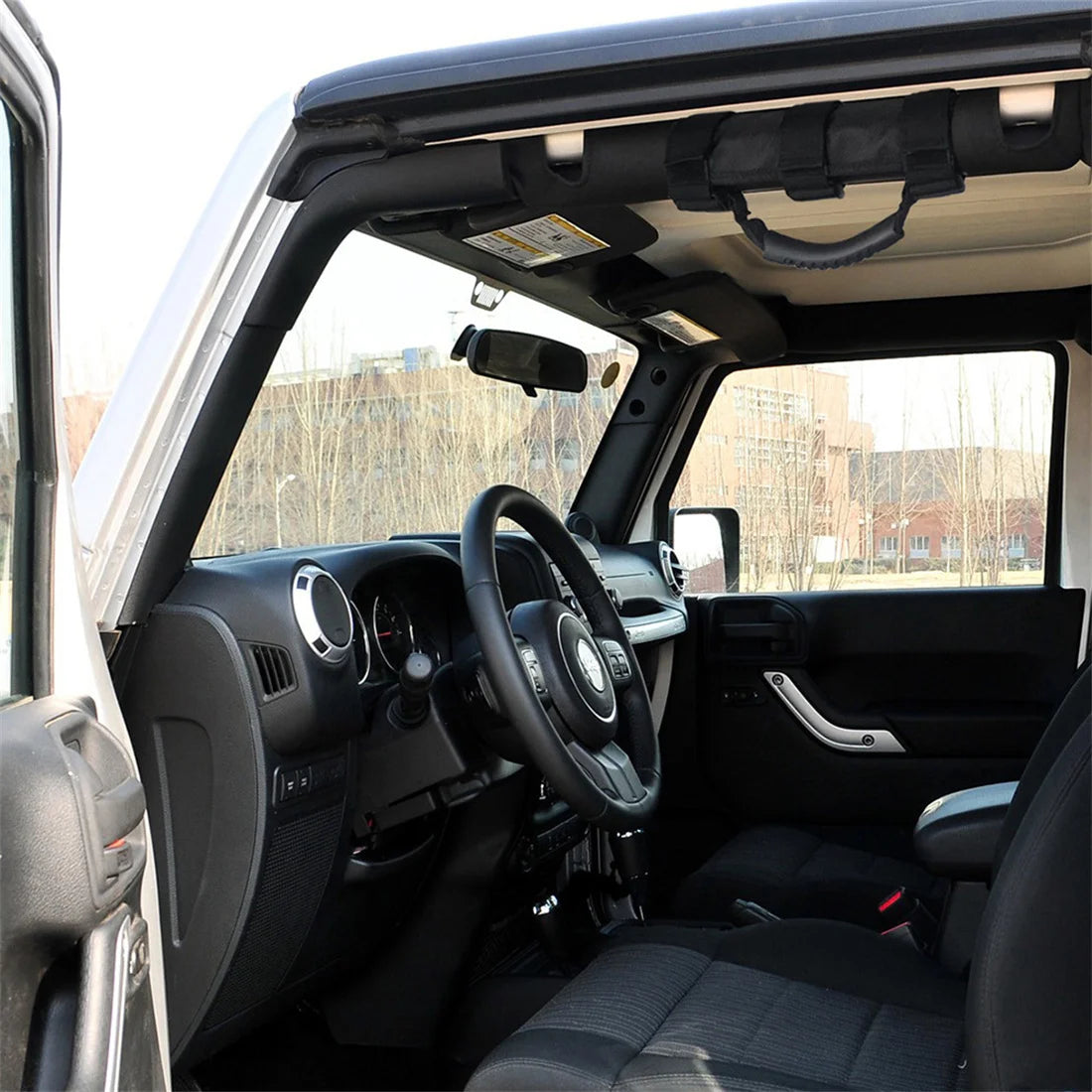 Interior view of a Jeep Wrangler showing non-slip roll bar grab handles installed on the door frame.