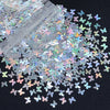 A close-up view of shiny holographic star sequins scattered on a dark surface.
