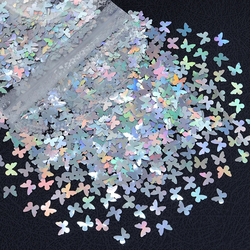 A close-up view of shiny holographic star sequins scattered on a dark surface.