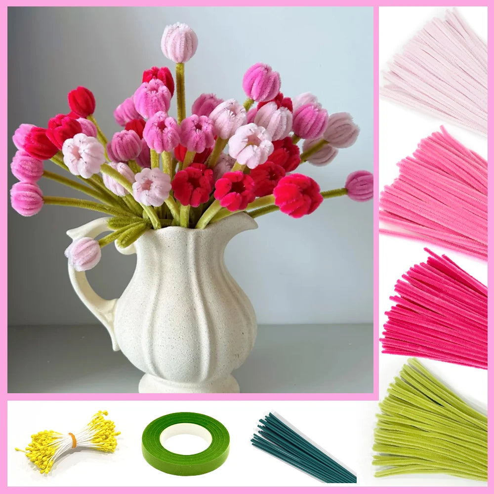A bouquet of pink and red pipe cleaner flowers in a white vase with various colored pipe cleaners and a green ring.