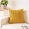 A yellow corduroy pillowcase with a striped velvet design resting on a white surface.