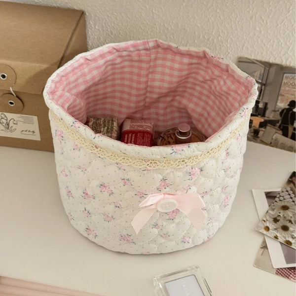 Cesta de almacenamiento acolchada blanca con forro de guinga rosa y lazo de cinta rosa.