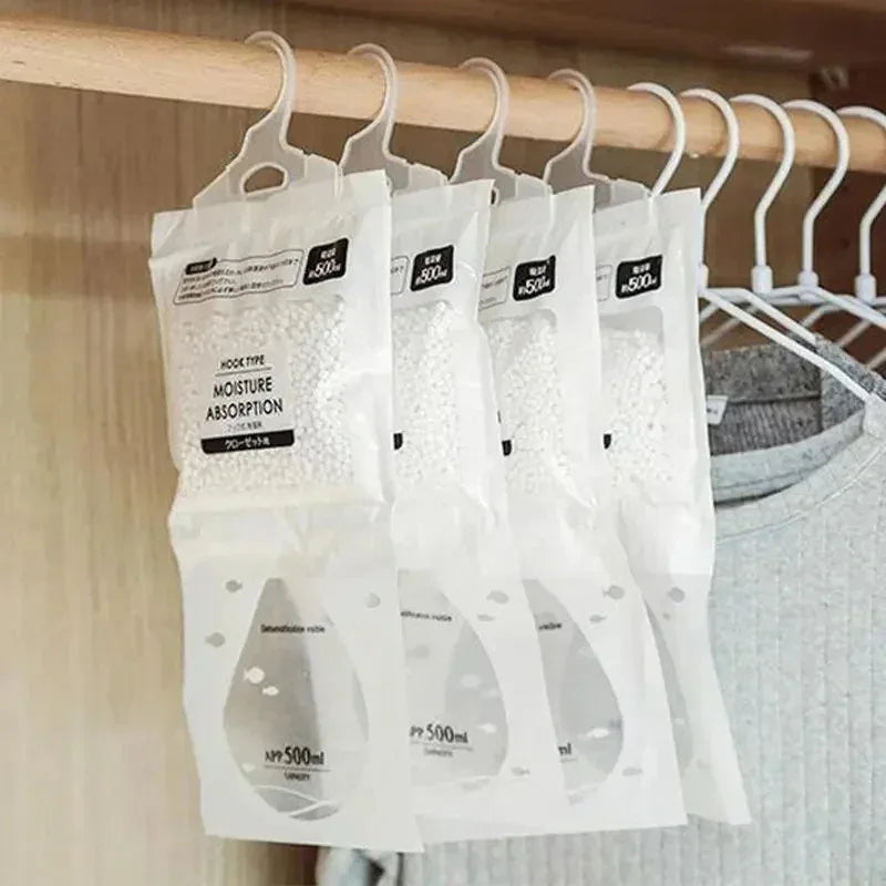 White moisture absorption bags hanging on a wooden rod in a closet