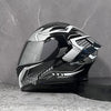 A black modular flip-up motorcycle helmet with silver and white graphic accents resting on a gray surface.