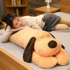 An extra-large soft orange dog plush pillow lying on a gray surface.