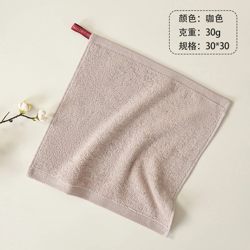A light beige organic cotton face towel is shown flatly on a surface.