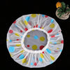 A white waterproof shower cap with colorful polka dots and a small succulent plant.