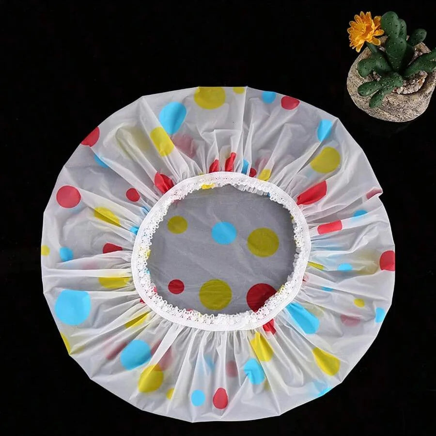 A white waterproof shower cap with colorful polka dots and a small succulent plant.