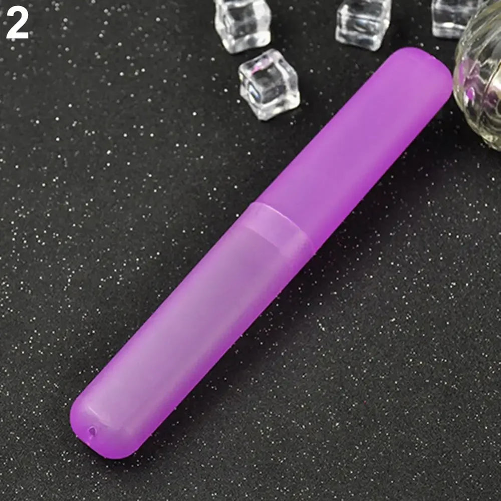 A purple travel toothbrush case with a translucent cap is shown on a dark surface next to small clear objects.