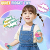 A smiling toddler holds a purple stress ball while wearing denim overalls, demonstrating a quiet fidget toy.