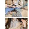 A woman models a beige vintage lace long sleeve blouse and jeans.