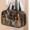 A transparent PVC travel toiletry bag filled with various glass bottles and toiletries.