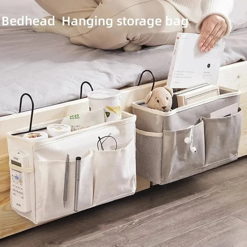 A beige hanging storage bag organizer with cotton pockets and a small stuffed animal on a wooden shelf.