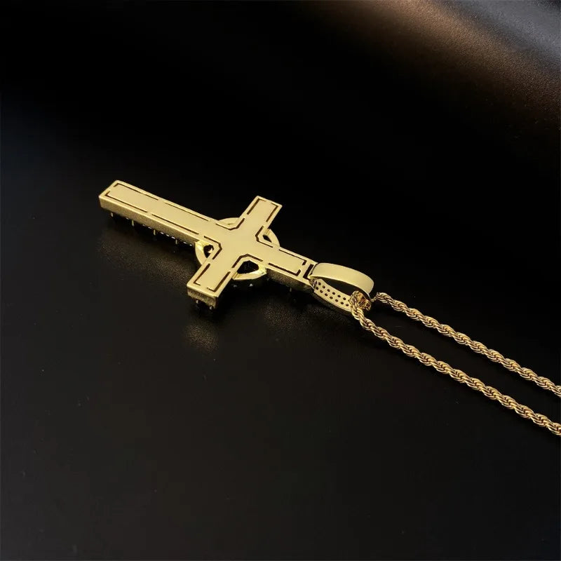 Pendentif de croix celtique en or serti, posé sur une surface sombre.