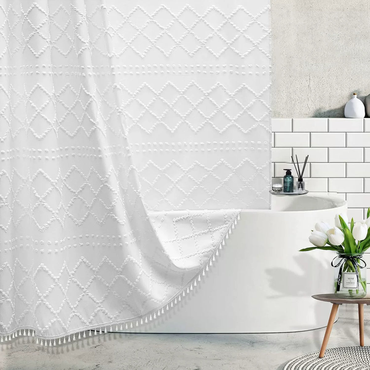 White boho waterproof shower curtain with diamond pattern and tassels hanging over a modern bathtub.