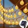String lights with gold-colored bulbs hanging outdoors, alongside a solar panel device.