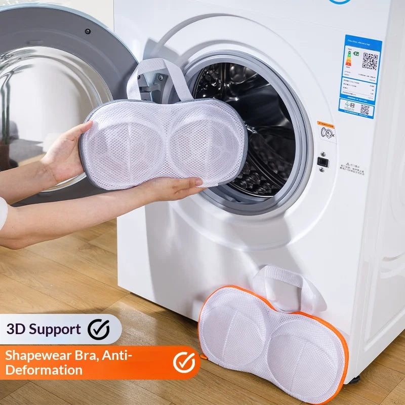 A hand places a mesh laundry bag for bra support into the drum of a white washing machine.