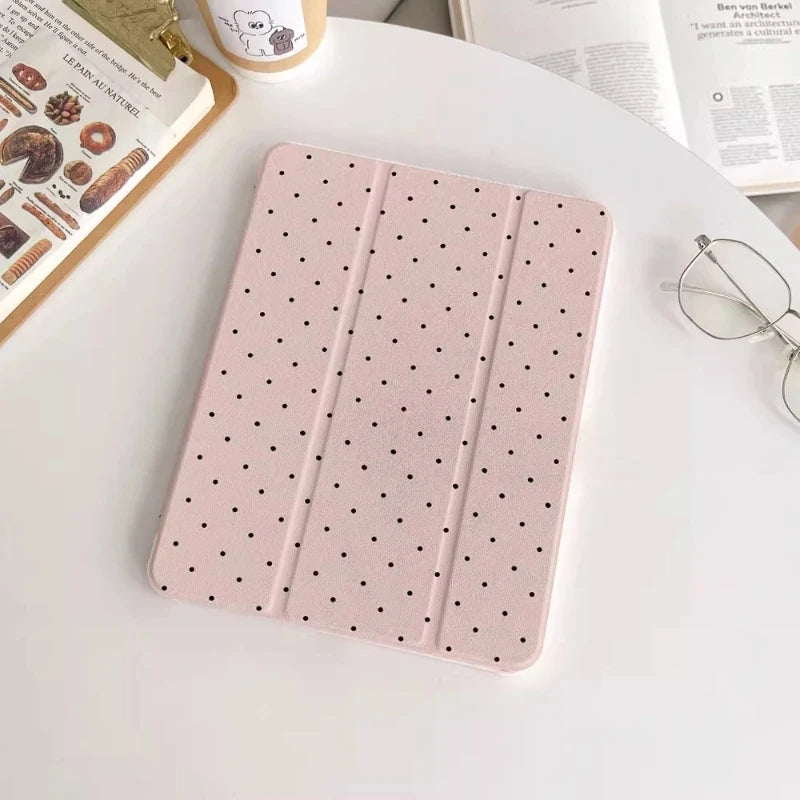 Rosa Schutzhülle für iPads mit gepunktetem Muster auf weißem Tisch.