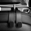 Close-up of black car headrest hooks designed for hanging bags and shopping organizers.
