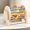 A wooden baby rattle bell with colorful rings is shown, demonstrating its soothing motion.