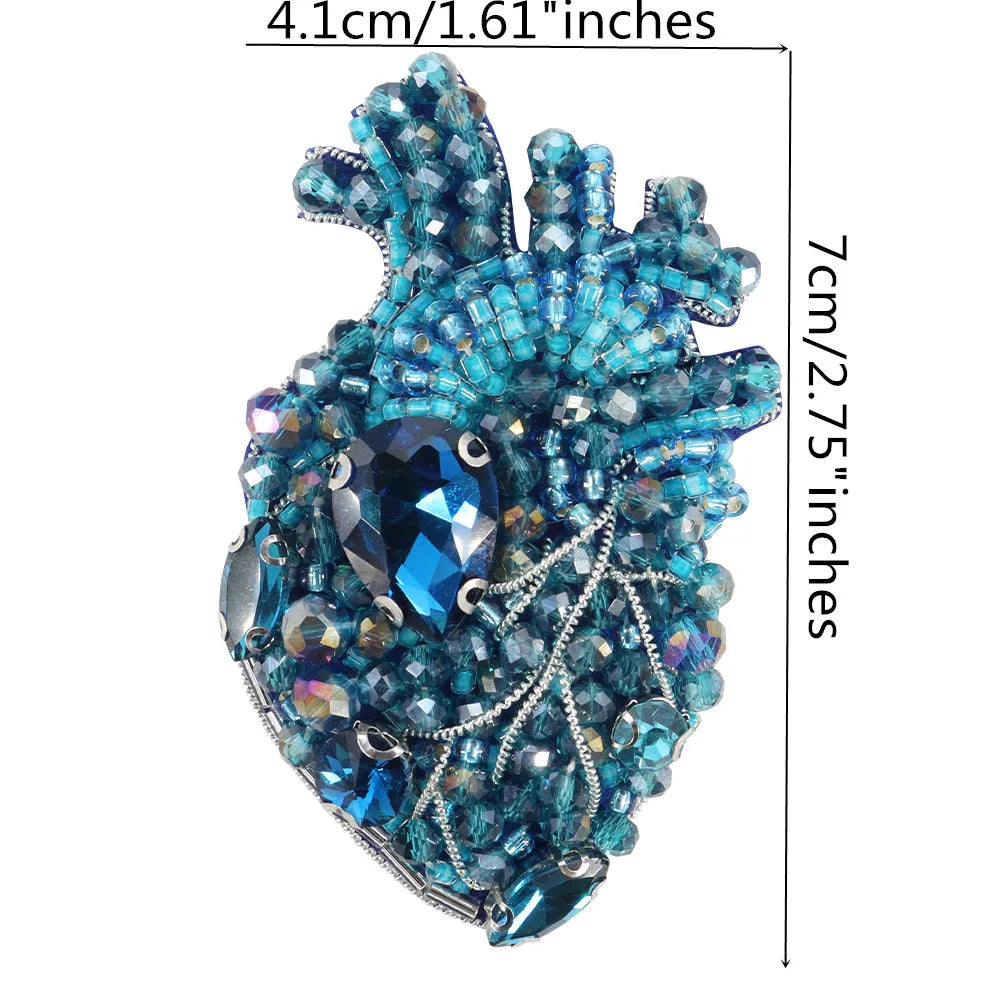 A sparkling blue and silver beaded rhinestone patch shaped like a heart or flame for clothing and crafts.