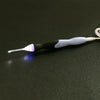 A black and white rechargeable LED crochet hook set with interchangeable heads resting on a dark surface.
