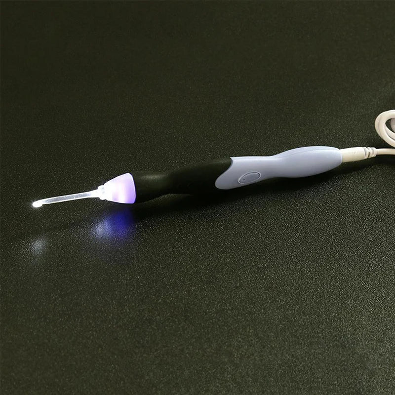 A black and white rechargeable LED crochet hook set with interchangeable heads resting on a dark surface.
