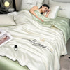 A white ultra-soft comforter with gold embroidery is displayed on a bed, featuring the word always.