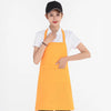 A woman wearing an orange waterproof apron over a white shirt and a black cap.