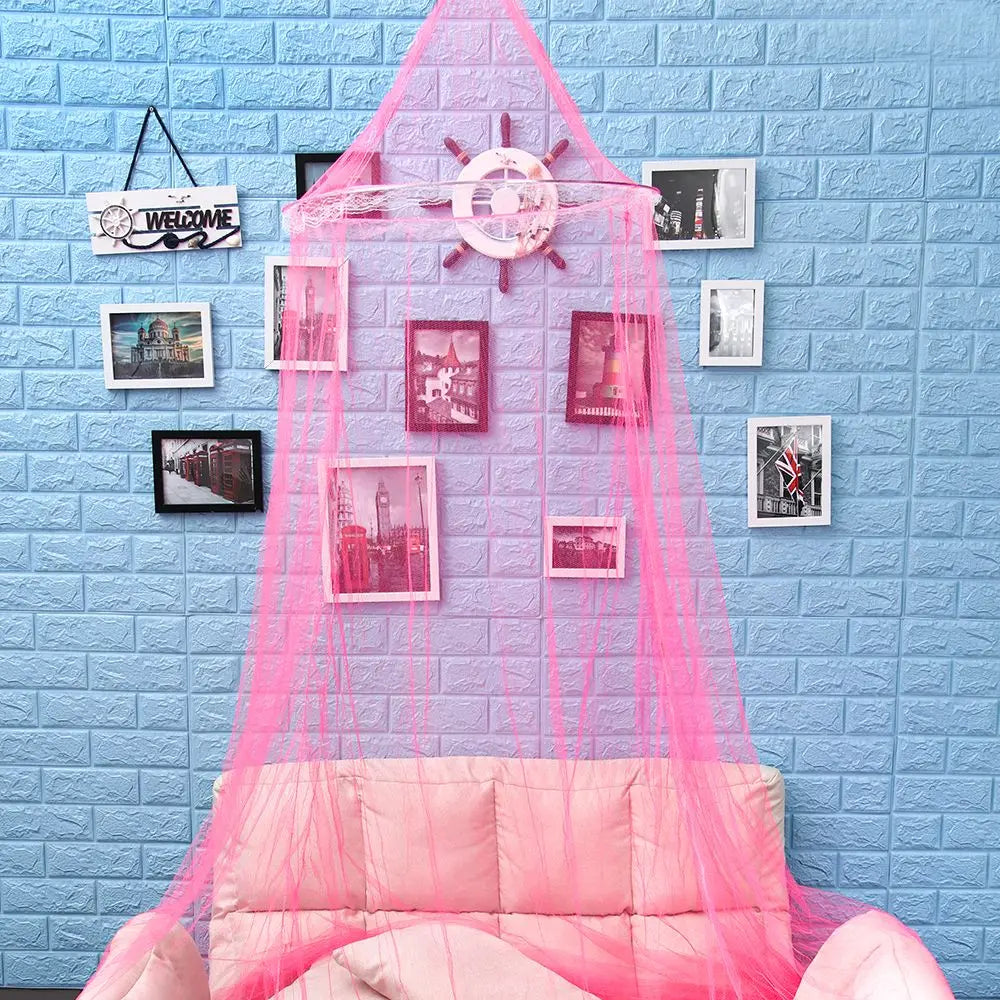 Elegant pink lace canopy mosquito net draped over a light blue brick wall with framed photos.