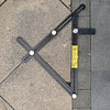 A black foldable aluminum angle ruler with locking segments is shown measuring a corner on a gray tiled surface.