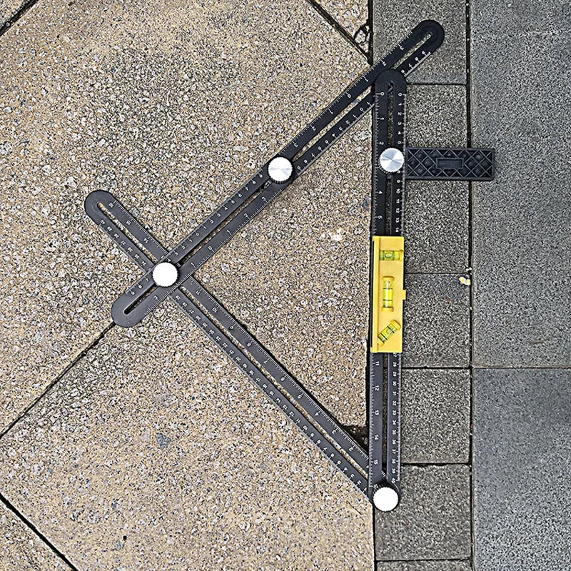 A black foldable aluminum angle ruler with locking segments is shown measuring a corner on a gray tiled surface.