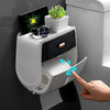 Una mano opera un soporte para papel higiénico impermeable montado en la pared con un smartphone y un reloj negros.