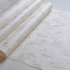 Rolls of embossed damask wallpaper featuring a delicate floral design on a white background.