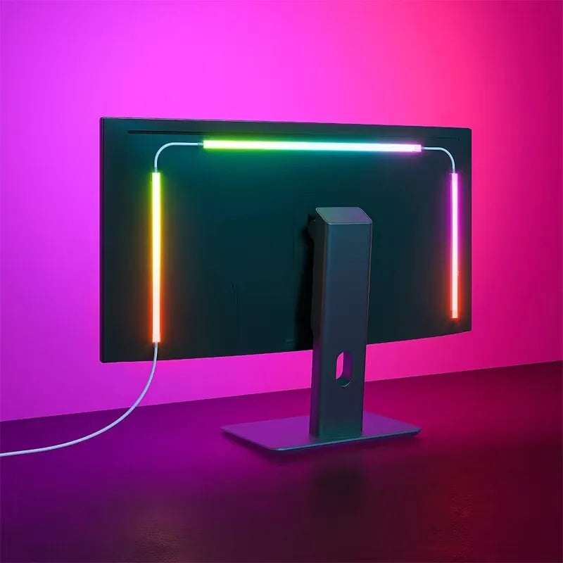 A black monitor is illuminated by a green and pink LED backlight strip, set against a vibrant magenta background.