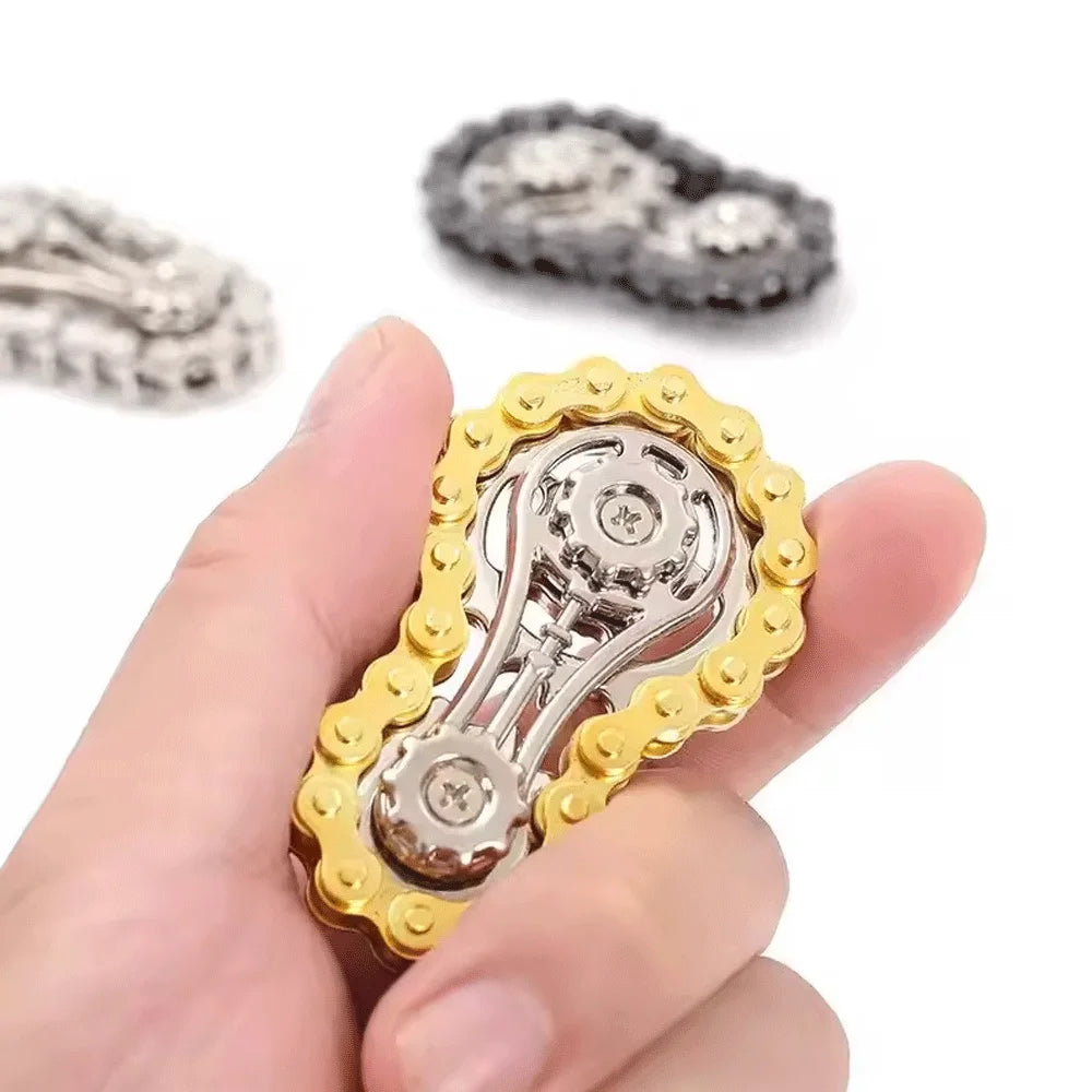 A hand holds a gold-toned sprocket fidget spinner, a metal desk toy for stress relief.