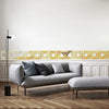 A modern living room featuring a gray sofa, a light wood floor, and a decorative gold mirror border above the sofa.