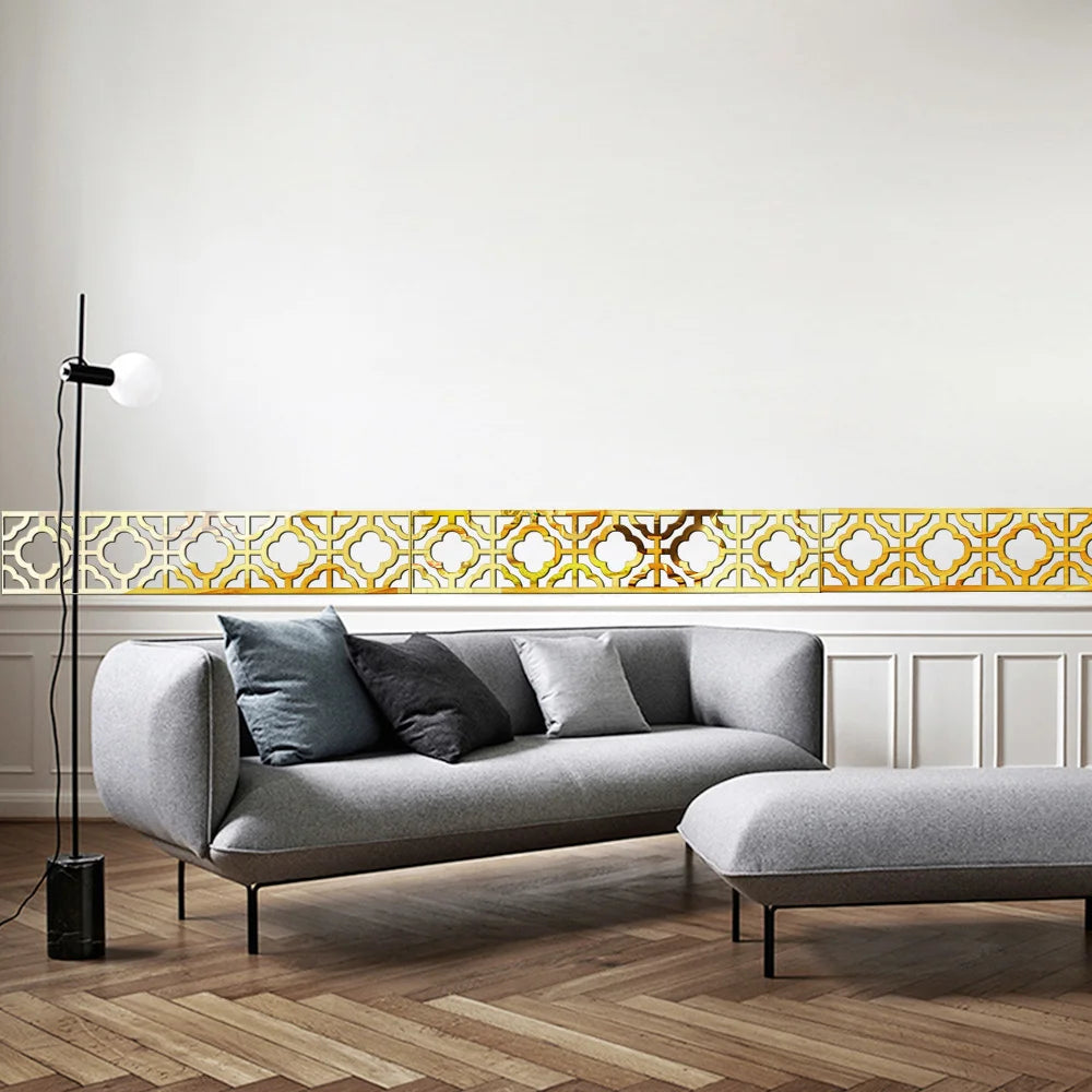 A modern living room featuring a gray sofa, a light wood floor, and a decorative gold mirror border above the sofa.