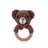 A brown crochet teddy bear shaped like a bunny with a white letter T on its chest, attached to a natural wood teether ring.